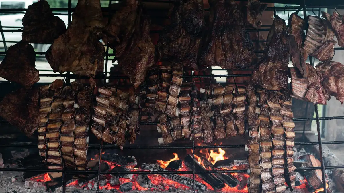 Asado argentino con tira de asado, chorizo y morcilla a la parrilla con chimichurri al lado